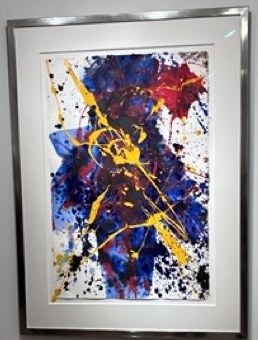 一幅装框的抽象纸上作品，带有蓝、红、黄色泼溅