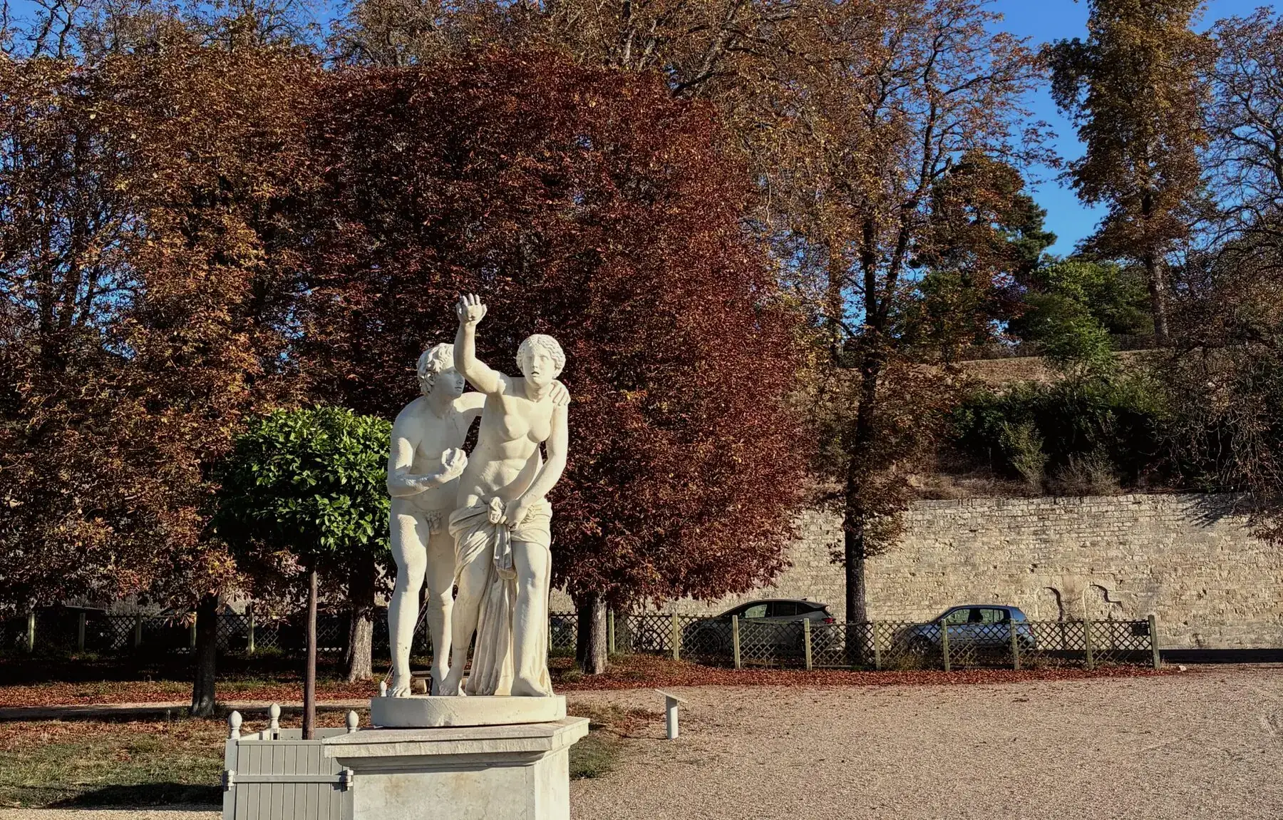 A classical statue in a Paris park surrounded by autumn trees