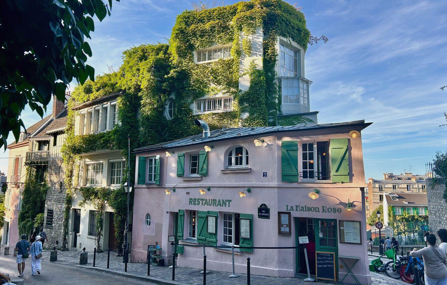 Ein mit Efeu bewachsenes rosafarbenes Restaurant an einer Straßenecke in Montmartre